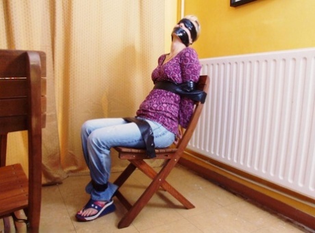 Caucasian woman is left tied and blindfolded in her clothes to a folding chair 94022917